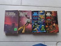 Photo of four Isaac Asimov books: The Universe From Flat Earth to Quasar, Isaac Asimov on Physics, The Invasions, and The Devils.