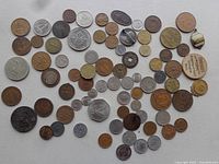 Photo showing many old world coins spread out on a flat surface, varied in size, metal color, and origin with some with square holes