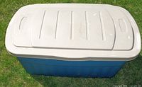 White lid of Rubbermaid outdoor storage box with no major damage visible except minor wear.