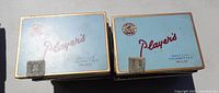 Two Player's Navy Cut cigarette tins with blue and red design showing brand name and sailor logo.