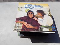 Photo of Captain Sensible album on top of stack with man in sunglasses and woman pointing finger on cover