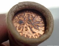 Close-up image of the end of a paper roll showing a 1975 Canadian penny, featuring a maple leaf design.