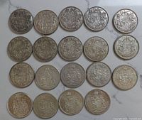 Twenty Canadian 50 cent silver coins arranged in four rows of five, reverse side showing Coat of Arms