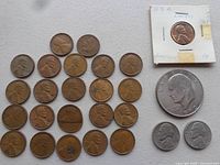 Image showing 28 USA coins including multiple Lincoln pennies, one in a paper holder marked 1961, a large 1964 Kennedy half dollar, and three smaller silver coins