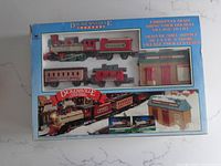Front view of the original box containing the Dickensville Christmas train set, showing all included train cars and station building inside a windowed box.