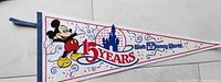 Photo of a vintage Walt Disney World 15 years celebration pennant with Mickey Mouse, Cinderella's Castle, and colorful graphics
