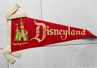 Vintage Disneyland felt pennant with castle image and Disneyland text, showing condition and design details.