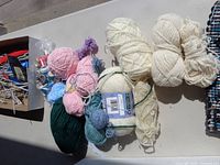 Yarn and wool skeins in different colors and sizes, displayed in natural light