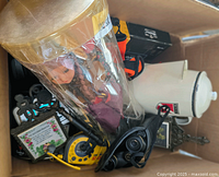 Box containing various collectible dolls, kitchenware, framed plaques, and other items.