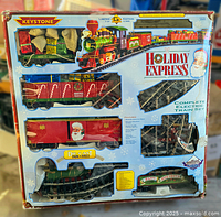Front view of boxed Keystone limited edition Holiday Express complete electric train set. Shows locomotive, gondola car with gifts, boxcar with Santa, tracks, and branding on box.