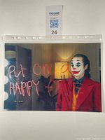 Full view of the signed Joker photograph showing the character in costume with 'Put on a happy face' text and autograph on the chest area.