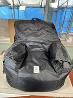 Black Big Joe brand beanbag chair, showing chair in sitting form with handle on backrest.