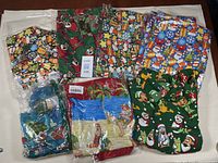 Photo of nine new assorted men's Christmas shirts by Brenda in various colorful patterns and sizes on a table.