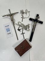 Two crosses, two rosaries with white beads and small crosses, and one brown leather pouch.