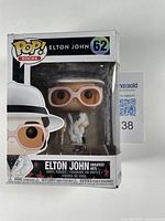 Photo of Elton John Funko Pop! vinyl figure in original box labeled Pop! Rocks #62 with minor box wear visible.