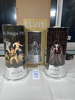 Two Elvis Presley rotating lamps displayed with one original box behind them. Both lamps show different Elvis themed artwork and have silver bases with Elvis signature and '68' Special' marking.