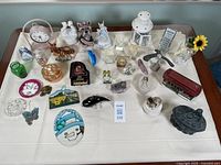 Overview of assorted knick-knacks including figurines, glass items, a streetcar model, and a vintage clock arranged on a table.