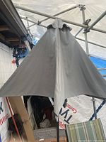 Full view of patio umbrella closed, showing dark fabric canopy attached to metal pole.