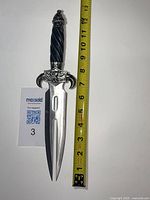 Full length photo of stainless steel dagger with measuring tape showing about 11.5 inches long, including blade and handle.