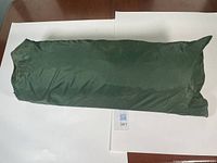 Green fabric tent carry bag laid flat on white surface for photo.