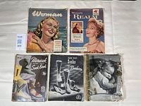 Two vintage women's magazines and five vintage knitting books laid out on a table, showing illustrated covers and wear consistent with age