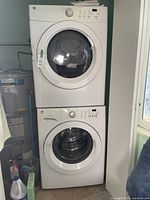Front view of white Kenmore stackable washer and dryer set in laundry room next to water heater and window