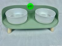Top-down view of the M-Pets double raised pet bowl showing two white bowls fitted into a green tray with light wood legs.
