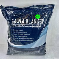 Photo of sealed sauna blanket in dark blue packaging with the product name and usage instructions printed on front.