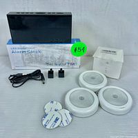 Full lot showing LED digital alarm clock, three motion sensor lights, power cable, two power adapters, mounting adhesives, and accessory box.