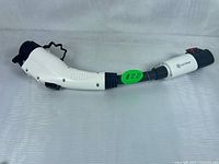 White and black Tesla to J1772 EV charging adapter with Lectron branding and ergonomic handle, shown fully from one angle.