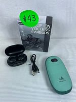 Photo showing black YYK-S19 wireless earbuds in open charging case, black USB charging cable, green UNIGEAR power bank, and earbuds packaging box.