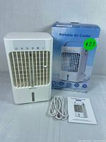 White portable air cooler model CD-107 with front grill, control panel on top, USB charging cable, user manual, and original retail box.