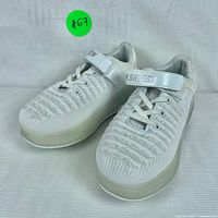 Front side angle view of two white fashion roller shoes with platform soles and lace-up fronts, one slightly behind the other, on white background.