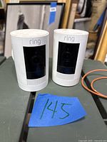 Front view of two Ring cameras side by side showing black lens panels and Ring logo
