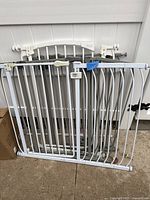 Five metal safety gates leaning against a wall, showing details of tension rods and locking parts.