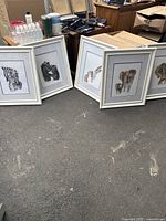 Five framed animal art pieces arranged on floor, showing overall condition and style of white wood frames.