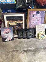 Wide view showing all 8 framed art pieces including Klimt's The Kiss, rural scene, floral print, trio of small black frames, decorative memo board, and mosaic panel.