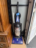 Full view of the Bissell PowerForce bagless upright vacuum cleaner with hose and crevice tool attached.