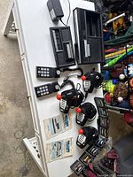 Full overview of ColecoVision system components including main console, expansion module, 6 controllers (2 keypad and 4 joysticks), game cartridges, and instruction manuals spread on table.