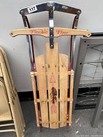 Overall top view of Flexible Flyer sled showing wooden slats with printed arrow and eagle, metal frame and steering bar with 'Flexible Flyer' text.