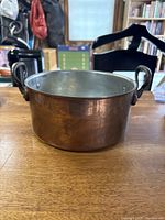Front view showing size and shape of the copper pot with metal handles and interior detail.