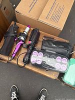 Photo showing purple curling wand, Revlon hot air hairbrush dryer, black cloth pouch, hair brush, and heated rollers set.