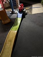 Long straight roller slide track made of yellow, green, and blue plastic sections set up on asphalt.
