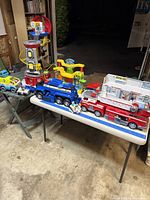 Wide shot of all included Paw Patrol trucks, playsets, and accessories on table