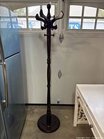 Full view of wooden hall coat rack standing beside appliances to show approximate height and style