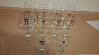 Set of 10 stemmed wine glasses arranged in two rows showing medium and small sizes with Olympic logo visible.