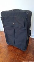Front view of black Samsonite suitcase showing zippered compartment and fabric texture