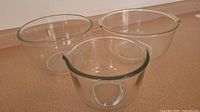 Set of three clear glass mixing bowls of varying sizes, nested, one with spout visible.