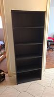 Front view of the sleek black wooden bookshelf showing all 6 shelves.