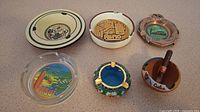 Full set of six souvenir ashtrays from Maui, Reno, California, and Cuba in various materials and colors.